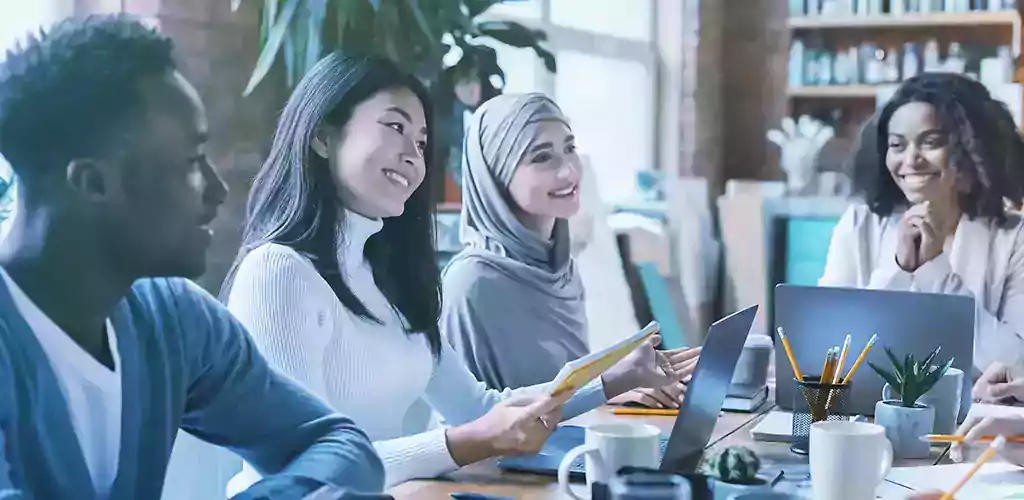 People sitting at a long desk working on laptops.