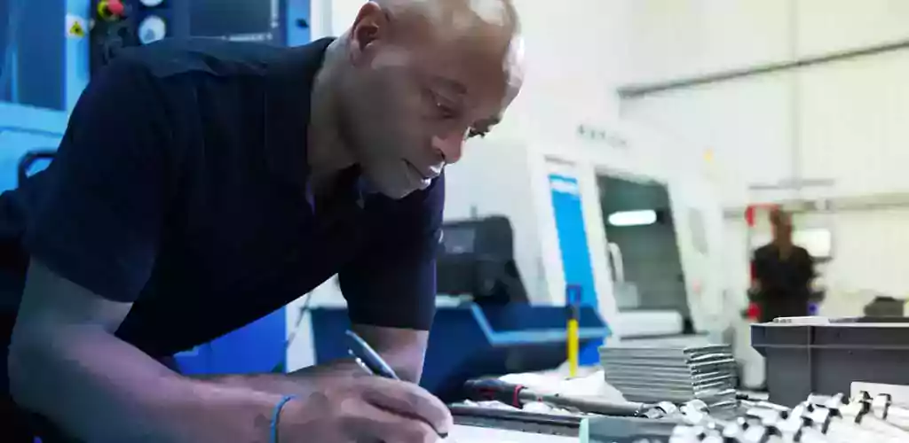 An engineer takes notes in a factory.